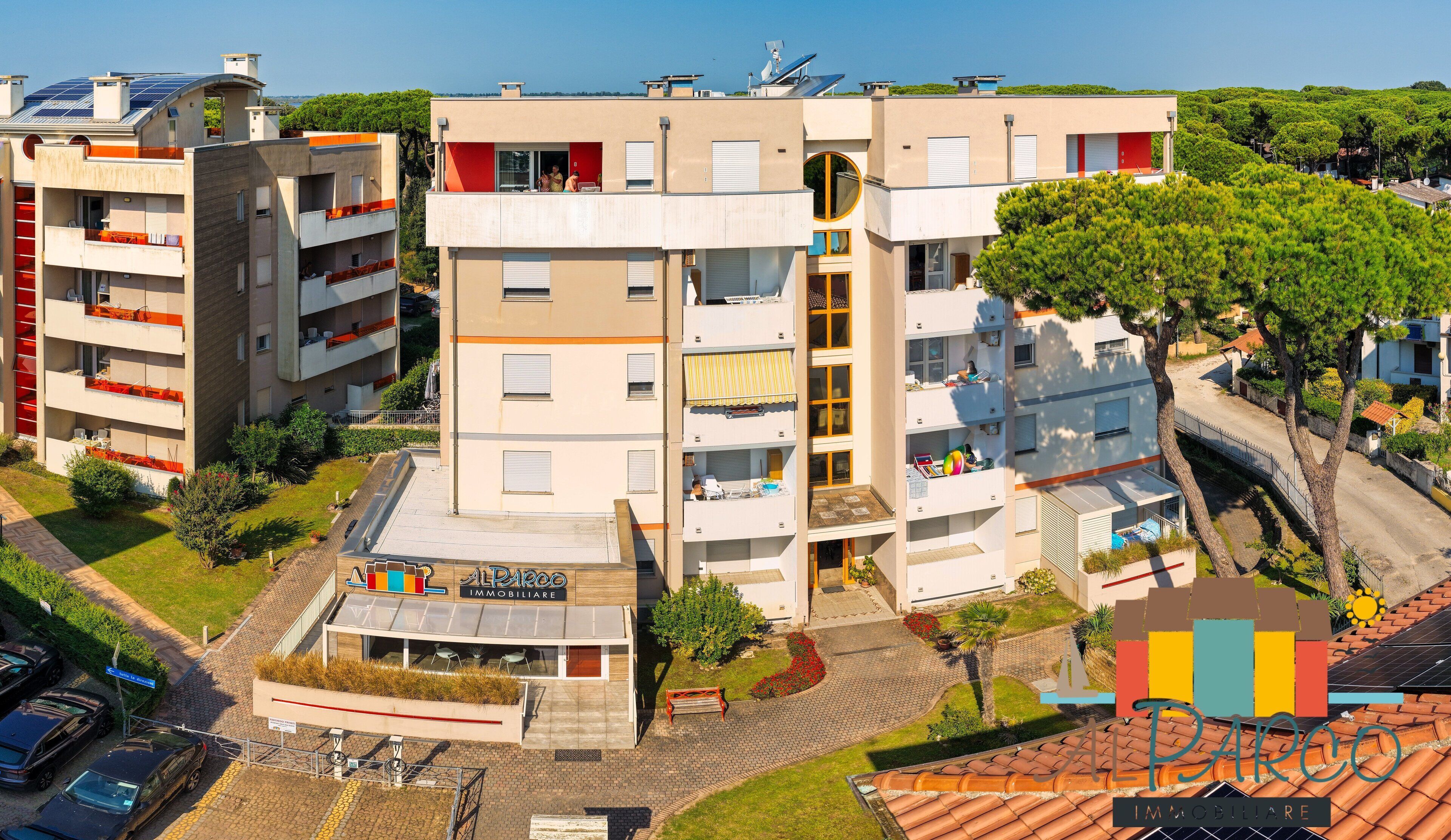 Un immeuble résidentiel à plusieurs étages, doté de balcons, de panneaux solaires et d’un petit espace extérieur aménagé en coin salon.