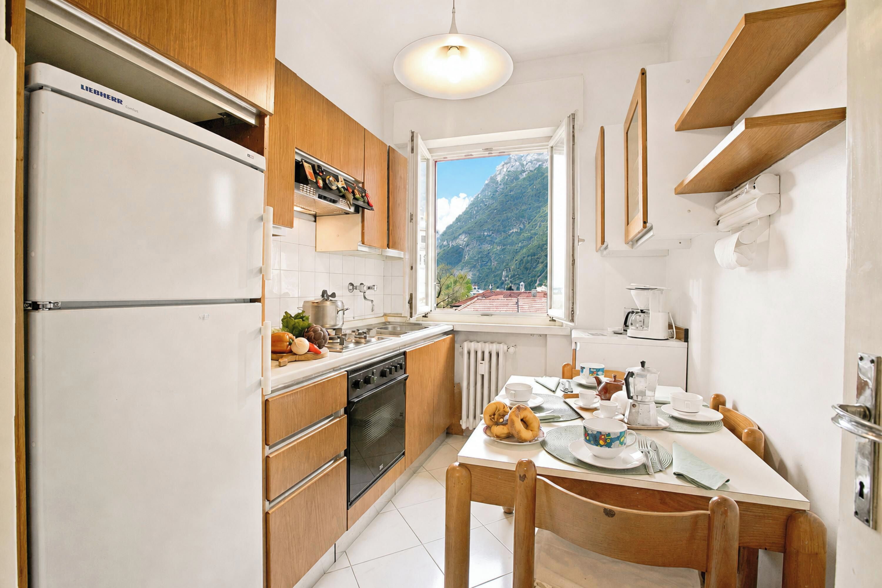 A modern kitchen with wooden cabinets, a built-in oven, and a dining area with a table and chairs.