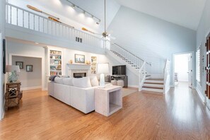 A spacious living area with a staircase, a fireplace, and a television.