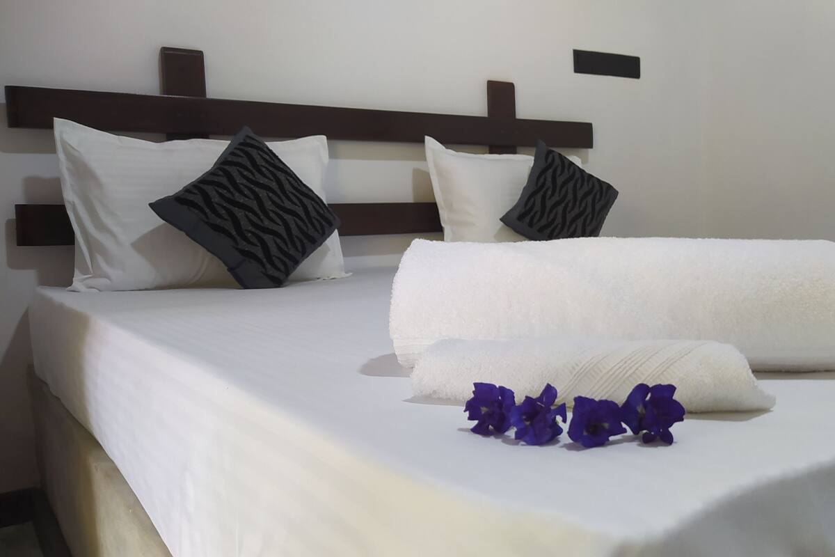 A neatly made bed with white linens, a headboard, and decorative pillows.