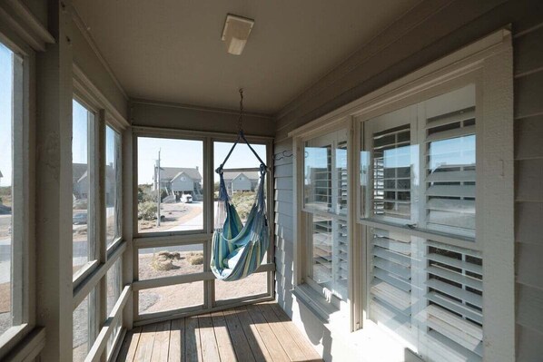 A covered porch with a hammock, large windows, and a view of the surrounding area. - Water Views with Pool and Beach Access! (Topsail Beach)