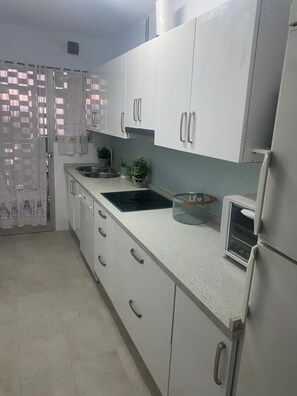 A kitchen with white cabinets, a sink, a stove, and a refrigerator.