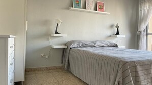 Ein Schlafzimmer mit einem Bett, zwei Nachttischen, einer Kommode und einem Regal mit drei gerahmten Bildern.