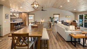 A spacious living area with a wooden dining table, a sofa, and a balcony with a view. - Mill Creek Rd Lakehouse (Ronald)