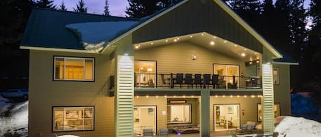 Eine zweistöckige Lodge mit Balkon, Kamin und verschneitem Gelände.