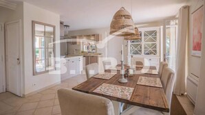 A dining area with a wooden table, chairs, and a hanging light fixture. - Provençal villa with sea view (STE MAXIME)