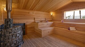 A wooden sauna with benches, a stone fireplace, and a window overlooking a beach. - Royal Teos Thermal Resort Clinic & Spa - Halal Hotel (Seferihisar)