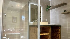 Une salle de bain moderne avec une douche à parois de verre, des étagères en bois et un miroir.