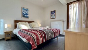 Une chambre d’hôtel avec un lit, une table de chevet, un radiateur et une fenêtre avec des rideaux.