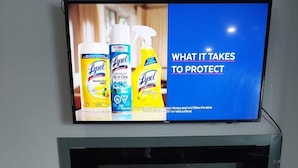 A television displaying Lysol disinfecting wipes, a fireplace, and a wooden coffee table with children's books and a remote control. - 3 minutes to the lake for.  lower suite with separate entrance.  (chestermere)