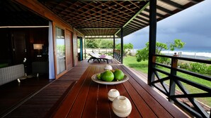 Une terrasse en bois avec une table, des chaises et une vue sur l’océan.