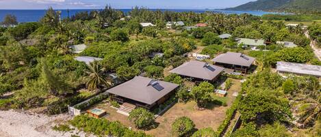 A coastal resort with multiple buildings surrounded by lush greenery and a beach.
