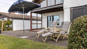 A patio with outdoor furniture, an umbrella, and a view of a house.