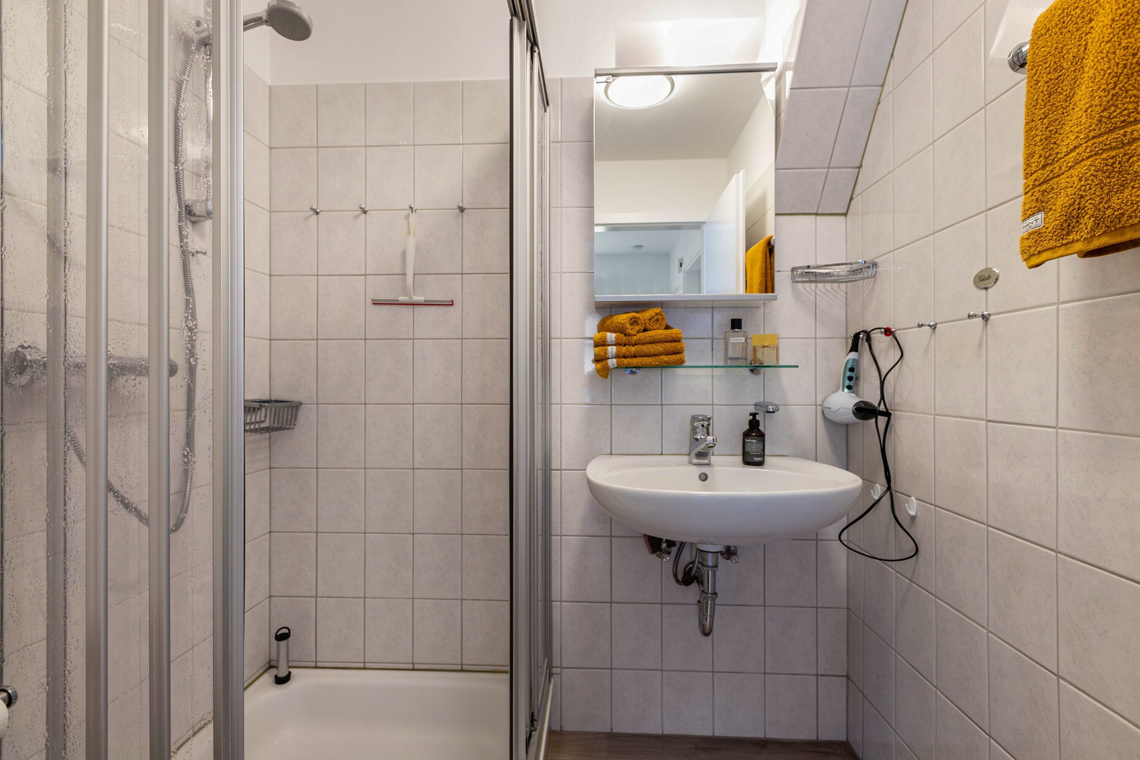 Une salle de bain avec une douche à parois de verre, un lavabo blanc et un miroir au-dessus.