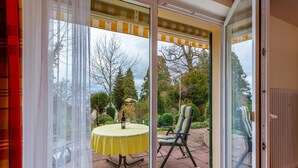 Ein Zimmer mit einer Schiebetür und Zugang zu einer Außenveranda, komplett mit Tisch und Stühlen.