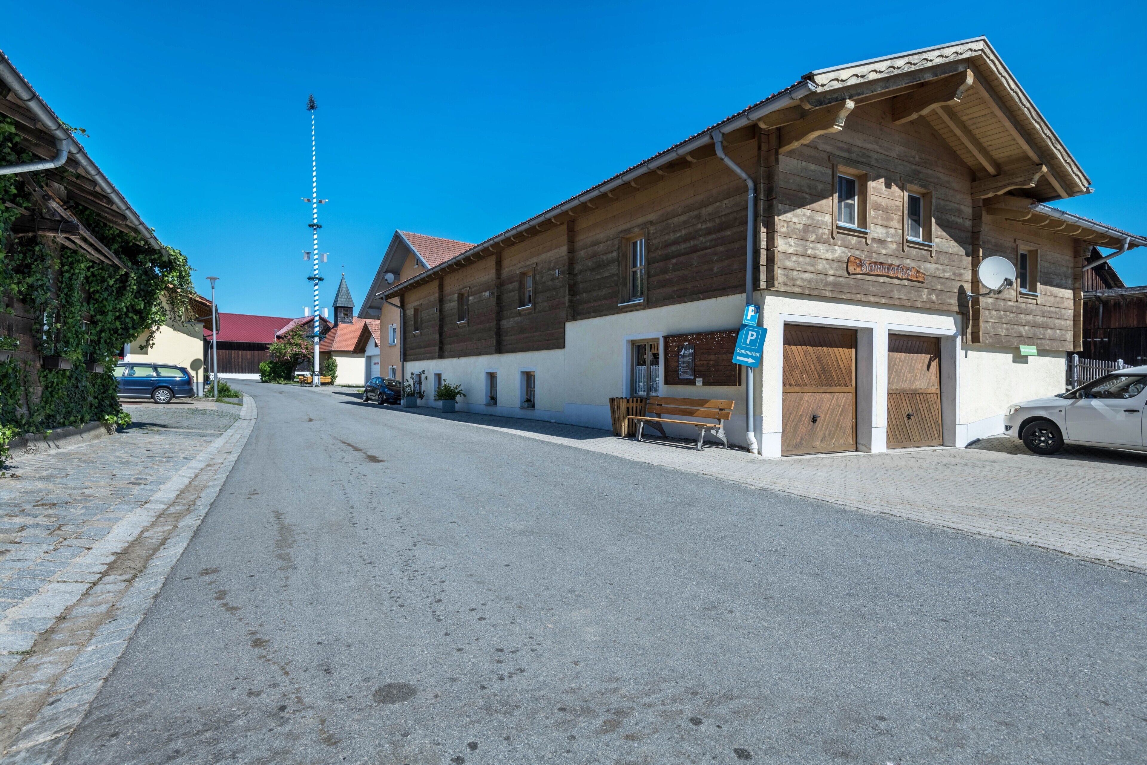 Une rue avec un bâtiment en bois, un banc et une voiture.