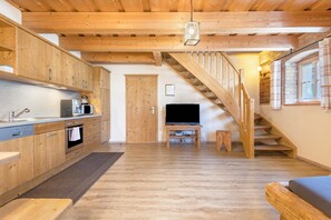 A wooden interior with a kitchen, a TV on a stand, and a staircase. - Apartment 'Ferienwohnung Stod´l' with Private Pool, Private Terrace and Wi-Fi (Freyung)