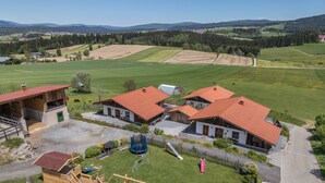 Ein ländliches Anwesen mit mehreren Gebäuden, einem Spielplatz und weitläufigen Feldern.