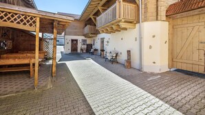 Ein überdachter Außenbereich mit Holzbänken, einem Holzzaun und einem Gebäude mit Balkon.