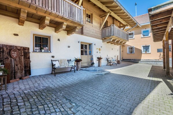 A courtyard with cobblestone pavement, wooden balconies, and a bench. - Apartment 'Ferienwohnung Stod´l' with Private Pool, Private Terrace and Wi-Fi (Freyung)
