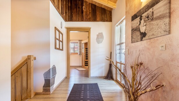 Eine Holztreppe, ein Teppich, eine Steinwand und ein Gemälde an der Wand.