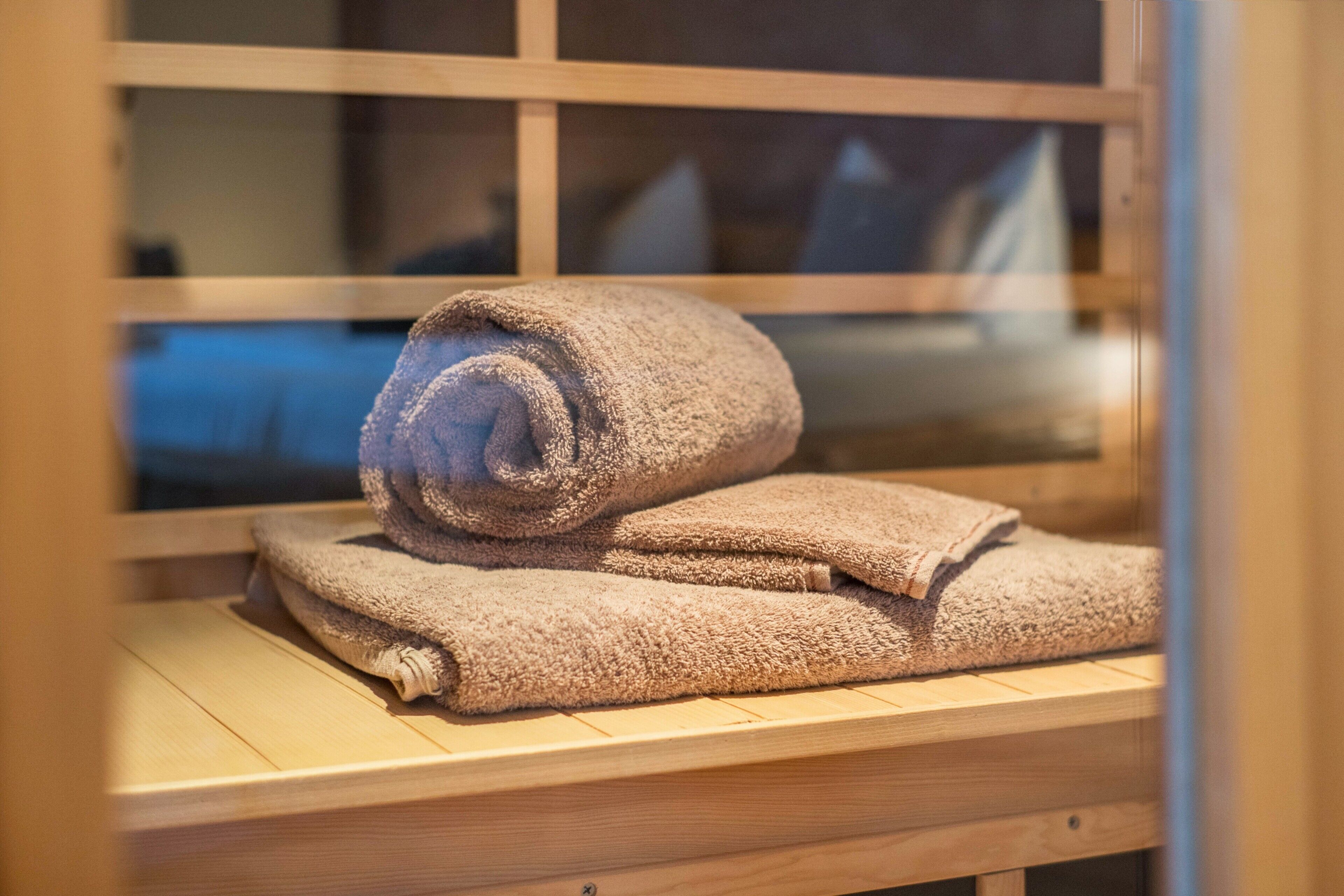 Een houten bank met opgerolde handdoeken.