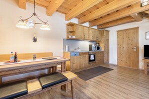 A wooden kitchen with a bench, a clock, and a television. - Apartment 'Ferienwohnung Stod´l' with Private Pool, Private Terrace and Wi-Fi (Freyung)