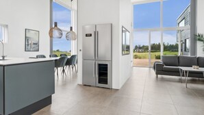 A modern kitchen with a large island, stainless steel appliances, and a dining area with chairs and pendant lights.