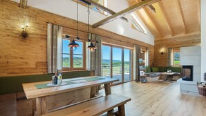 A spacious room with wooden walls, large windows, a wooden bench, and a fireplace. - Chalet 'Bergchalet 3' with Private Pool, Private Terrace and Wi-Fi (Freyung)