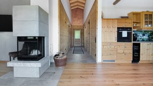 A modern interior with a fireplace, wooden flooring, and a kitchen area. - Chalet 'Bergchalet 3' with Private Pool, Private Terrace and Wi-Fi (Freyung)