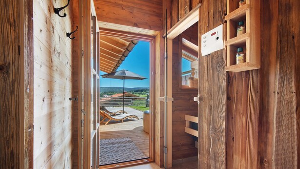 A wooden interior with a glass door leading to an outdoor deck with a view of the countryside. - Chalet 'Bergchalet 3' with Private Pool, Private Terrace and Wi-Fi (Freyung)