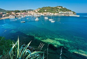 A coastal town with clear blue waters, boats, and a hilltop settlement. - Sogno Azzurro (3) - Da Claudia (Porto Azzurro)