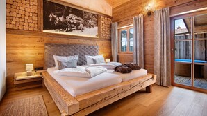 Un dormitorio de madera con cama, mesita de noche, un cuadro en la pared y puerta corrediza de vidrio.