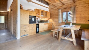 Un interior de madera con cocina, comedor y ventana con cortinas.