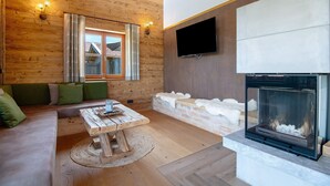 A log cabin interior with a fireplace, wooden walls, a sofa, and a television. - Chalet 'Bergchalet 1' with Private Pool, Private Terrace and Wi-Fi (Freyung)