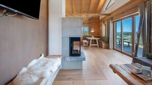 A modern interior with a fireplace, wooden flooring, a flat-screen TV, and large windows offering a view. - Chalet 'Bergchalet 1' with Private Pool, Private Terrace and Wi-Fi (Freyung)