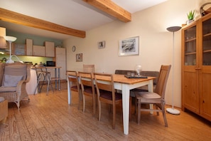 A dining area with a wooden table, chairs, a sofa, and a cabinet. - Apartment "Poggenkrug Halbsguth" with Lake View, Private Terrace & Wi-Fi (Wolgast)