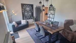 Una sala moderna con comedor, que incluye un gran cuadro de Buda, una mesa de madera y una acogedora zona de estar.