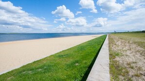 A beach with a grassy path leading to the water, a clear sky, and distant land. - Holiday Home 'Ferienhäuser Familie Täubert' with Private Terrace, Private Garden and Wi-Fi (Boxberg/O.L.)