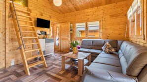A wooden cabin interior with a sofa, a coffee table, a TV, and a ladder. - Holiday Home 'Ferienhäuser Familie Täubert' with Private Terrace, Private Garden and Wi-Fi (Boxberg/O.L.)
