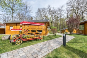 Une cabane en bois avec un vélo rouge et un auvent rouge.