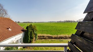 Vista desde un balcón sobre un campo verde y una lejanía de árboles.