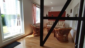 Una habitación con un ventanal grande, muebles de mimbre y una pared de acento roja.