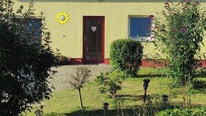 Un edificio con fachada amarilla, puerta roja y un adorno de sol en la pared.