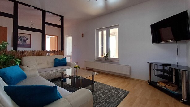 Una sala de estar con sofá, mesa de centro y televisor de pantalla plana en la pared.