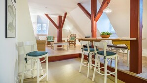 A dining area with white chairs, a wooden table, and a hanging light fixture. - Holiday flat "Kemenate" - individual flat under the roof (Trendelburg)