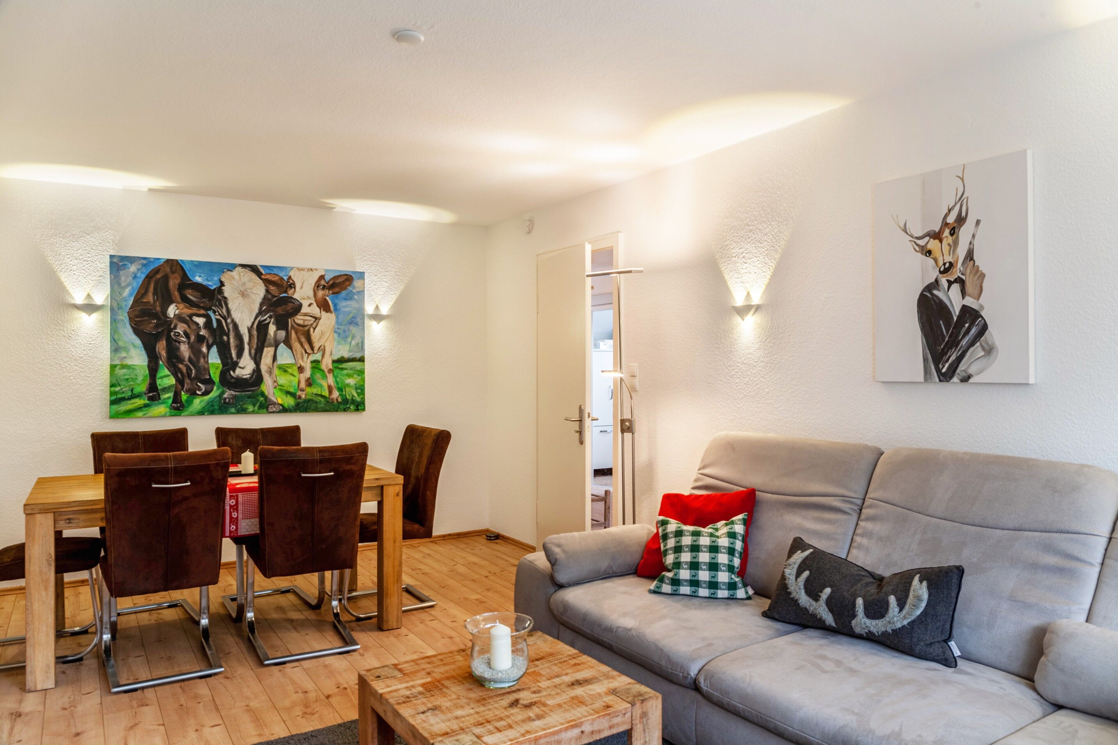 Un salon comprenant une table à manger, des chaises, un canapé et deux tableaux accrochés au mur.