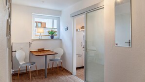 A compact kitchen with a window, a table with chairs, and a sliding glass door. - Apartment 'Ferienwohnung Alpenglück' with Mountain View, Terrace and Wi-Fi (Mittenwald)