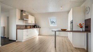 Eine moderne Küche mit weißen Schränken, einer Holz Arbeitsplatte und einem Fenster mit Blick.