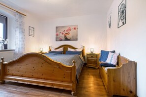 Un lit en bois avec une tête de lit, une table de chevet, un banc et un tableau accroché au mur.
